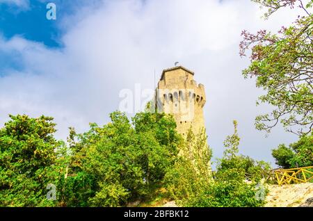 Repubblica San Marino Terza Torre Montale terza torre fortificata con muri in mattoni su roccia di Monte Titano con alberi verdi, vista dal basso, cielo blu w Foto Stock