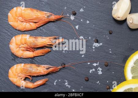 Gamberi rossi bolliti con aglio e limone su sfondo scuro Foto Stock