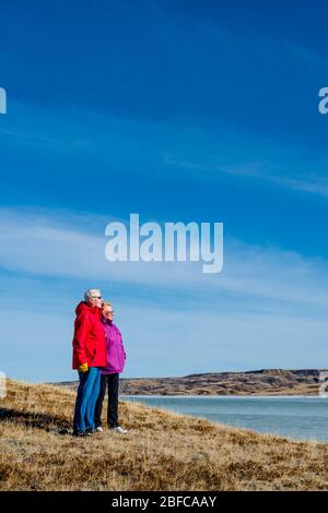 Coppia senior che si affaccia su un lago di Diefenbaker coperto di ghiaccio Foto Stock