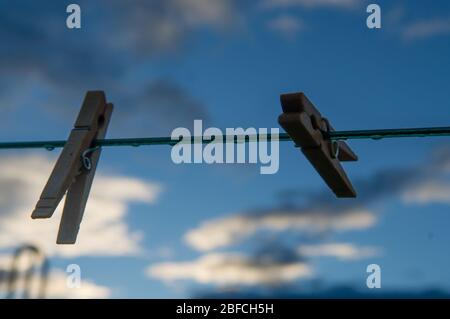 due spille di vestiti agganciati ad una linea vuota dei vestiti con le goccioline d'acqua da dopo una pioggia in un cortile urbano o rurale che simboleggia il lavoro domestico o il lavaggio Foto Stock