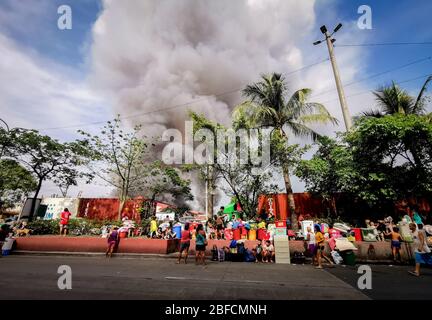 Distretto della capitale, Filippine. 18 Aprile 2020. (Nota per gli editori: Immagine acquisita dal dispositivo mobile). Gli evacuati hanno visto osservare indifesi lungo la strada mentre il fuoco ha spazzato attraverso "Happyland", un'area di baraccopoli a Manila il sabato, Barangay 105, zona 9, Distretto 1 e rapidamente si è diffuso, spingendo il Bureau of Fire Protection a sollevare l'allarme della Task Force Alpha o di livello intermedio. (Foto di Rick Mupas/Pacific Press) Credit: Pacific Press Agency/Alamy Live News Foto Stock