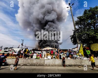 Distretto della capitale, Filippine. 18 Aprile 2020. (Nota per gli editor:immagine scattata dal dispositivo mobile). Gli evacuati hanno visto osservare indifesi lungo la strada mentre il fuoco ha spazzato attraverso "Happyland", un'area di baraccopoli a Manila il sabato, Barangay 105, zona 9, Distretto 1 e rapidamente si è diffuso, spingendo il Bureau of Fire Protection a sollevare l'allarme della Task Force Alpha o di livello intermedio. (Foto di Rick Mupas/Pacific Press) Credit: Pacific Press Agency/Alamy Live News Foto Stock