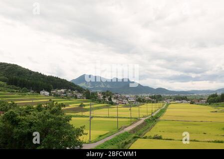 Vista panoramica ed epica di una strada nel mezzo dei risaie dalla collina, sul retro della catena montuosa e piste da sci attraverso la sk Foto Stock