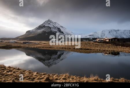 Tipico paesaggio invernale islandese con lago e montagne innevate nella zona di Arnarstapi in islanda Foto Stock
