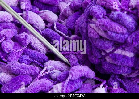 Un set di agugliature per la lavorazione a maglia. Primo piano di un bel filo viola e bianco con una palla e raggi. Foto Stock