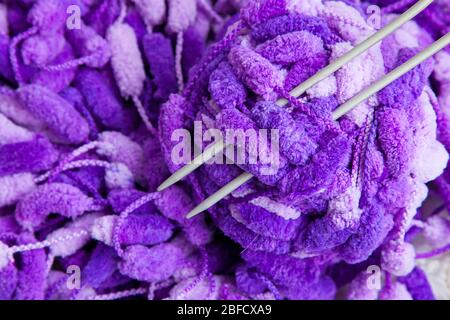 Un set di agugliature per la lavorazione a maglia. Primo piano di un bel filo viola e bianco con una palla e raggi. Foto Stock