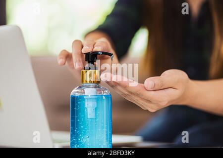 Closeup femminile asiatica utilizzando igienizzante mani pompando gel di alcol e lavando prima di lavorare con il laptop in casa, coronavirus o covid1 Foto Stock