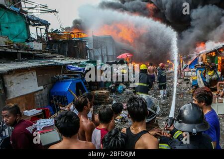 Manila, Filippine. 18 Aprile 2020. I vigili del fuoco tentano di spegnere un fuoco che inghiottisce una zona di baraccopoli a Manila, Filippine, 18 aprile 2020. Centinaia di famiglie qui sono state sfollate sabato a causa del fuoco. Credit: Rouelle Umali/Xinhua/Alamy Live News Foto Stock