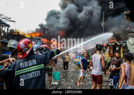 Manila, Filippine. 18 Aprile 2020. I vigili del fuoco tentano di spegnere un fuoco che inghiottisce una zona di baraccopoli a Manila, Filippine, 18 aprile 2020. Centinaia di famiglie qui sono state sfollate sabato a causa del fuoco. Credit: Rouelle Umali/Xinhua/Alamy Live News Foto Stock