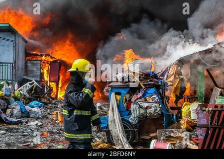 Manila, Filippine. 18 Aprile 2020. Un vigile del fuoco è visto da un incendio che inghiotte una zona di baraccopoli a Manila, Filippine, 18 aprile 2020. Centinaia di famiglie qui sono state sfollate sabato a causa del fuoco. Credit: Rouelle Umali/Xinhua/Alamy Live News Foto Stock