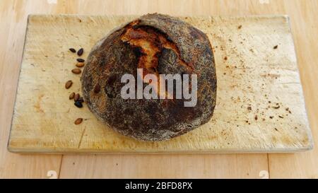 Il pane fatto in casa si siede su una tavola di pane in attesa di essere affettato Foto Stock