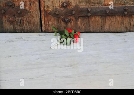 Un mazzo di fiori messo a terra davanti alla porta chiusa in legno del Santuario di nostra Signora del Carmelo, durante la chiusura Foto Stock