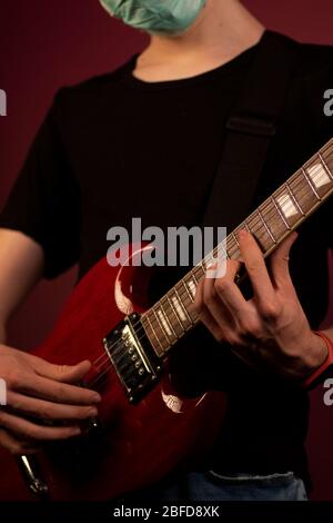 Coronavirus, quarantena a casa, chitarra in maschera di protezione Foto Stock