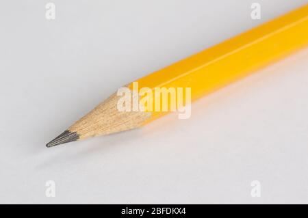 Un colpo di una matita gialla presa posando sul suo lato su uno sfondo bianco Foto Stock