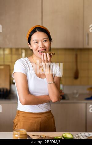 Donna che fa pane tostato al burro di arachidi per una sana colazione a casa Foto Stock