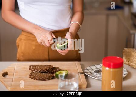 Donna che fa pane tostato al burro di arachidi per una sana colazione a casa Foto Stock