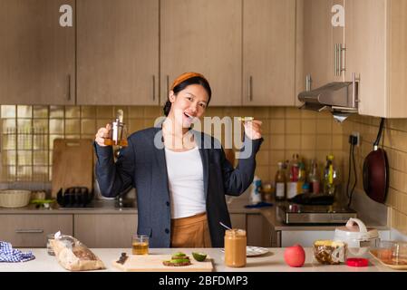 Allegra donna asiatica che si fida in cucina dopo aver trascorso troppo tempo all'interno Foto Stock