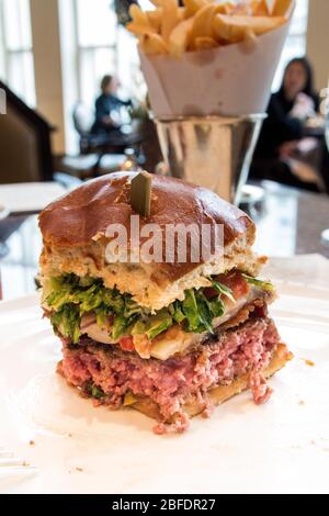 CHICAGO, ILLINOIS, STATI UNITI - DEC 12, 2015: Cheeseburger gourmet con patatine fritte in background in un ristorante di lusso Foto Stock