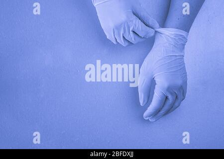 mani da donna in guanti in lattice per uso medico, blu tinto, copyspace Foto Stock