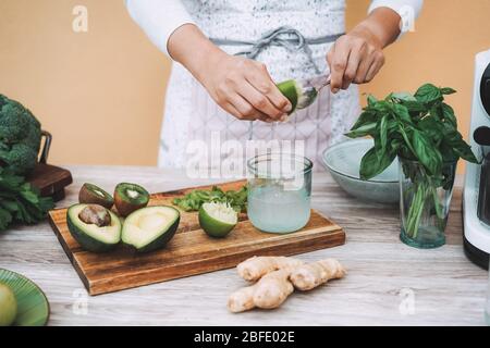 Giovane donna che prepara il succo di detox con estrattore a freddo - ragazza che fa frullati con verdure verdi e frutta - lifestyle sano nutri Foto Stock