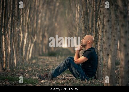 Uomo seduto con depressione che attraversa un cerotto ruvido nella sua vita, soffrendo di spossatezza mentale, ansia, burnout Foto Stock