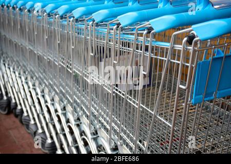 Molti carrelli per lo shopping. Carrelli per lo shopping blu e moderni per i supermercati in fila. Foto Stock