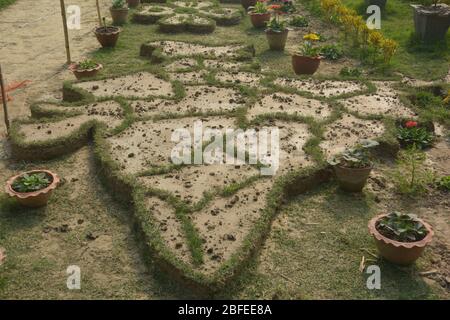 Primo piano della mappa indiana e dello Sri Lanka fatta a terra con fango e confini con erba tessuta in un giardino con vasi di fiori Foto Stock