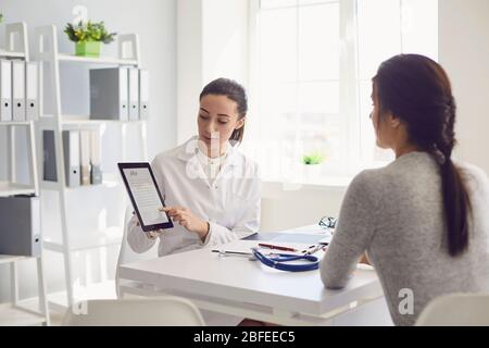 Paziente donna in visita medico femminile presso l'ufficio della clinica. Il lavoro medico scrive una prescrizione su un tavolo in un ospedale. Foto Stock