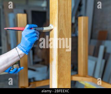 verniciatura di mobili in legno con spazzole e vernice nella falegnameria Foto Stock