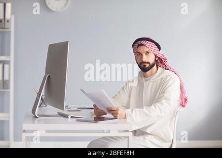 L'uomo d'affari arabo lavora in computer sul posto di lavoro in ufficio. Foto Stock