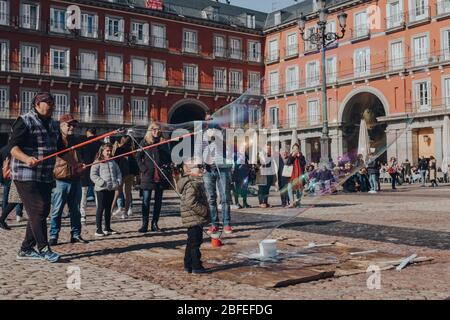 Madrid, Spagna - 26 gennaio 2020: Street performer crea una bolla di sapone intorno a un ragazzo in Plaza Mayor, uno spazio pubblico importante nel cuore di Madrid, Spa Foto Stock
