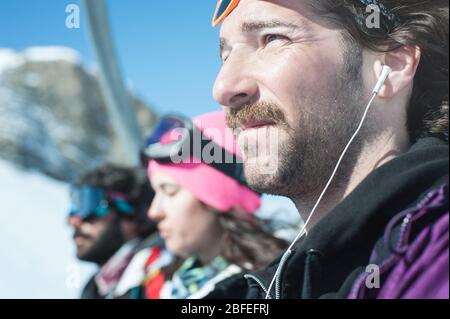 Primo piano di un gruppo di tre sciatori e snowboarder, donne e uomini, trasportati con gli impianti di risalita, goditi il bel tempo sulla montagna Foto Stock
