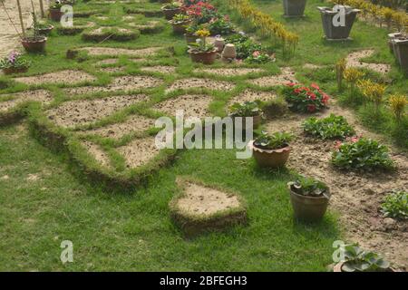 Primo piano della mappa indiana e dello Sri Lanka fatta a terra con fango e confini con erba tessuta in un giardino con vasi di fiori Foto Stock