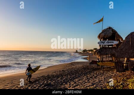 Las Penitas , Nicaragua - Febuary 21 , 2018 : surfisti che camminano sulla spiaggia al tramonto a Léon Nicaragua Foto Stock