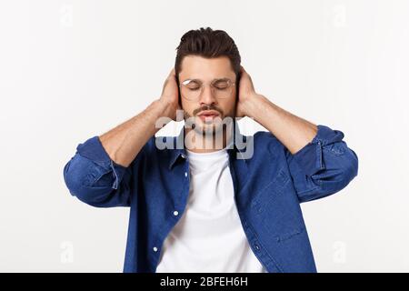 giovane uomo che copriva le orecchie, chiudendo gli occhi, isolato su sfondo bianco. Non senti il malvagio concetto. Emozioni espressioni facciali e segno di comunicazione Foto Stock