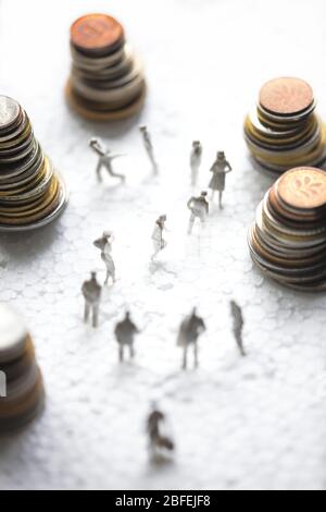 Piccole figure di plastica bianca stanno formando un punto interrogativo tra mucchi di vecchie monete europee. Foto Stock