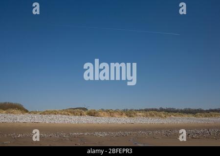 Cielo blu profondo sopra Newton Beach Porthcawl con solitario jet trail durante il blocco dei coronavirus Foto Stock