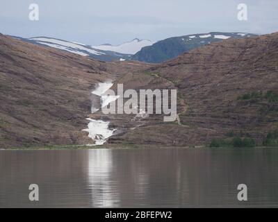 Lago naturale Svartivatnet e cascata sui paesaggi vicino al ghiacciaio europeo Svartisen nella contea di Nordland in Norvegia, cielo nuvoloso in 2019 freddo estate da Foto Stock