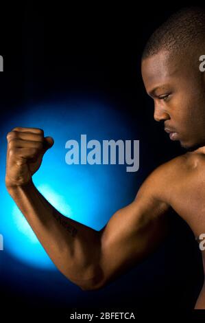 Un giovane maschio che tese il suo muscolo bicep destro Foto Stock