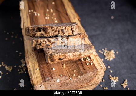 Pane di grano saraceno fatto in casa su sfondo scuro con grani. Pane fresco senza glutine, prodotti da forno tagliati a fette Foto Stock