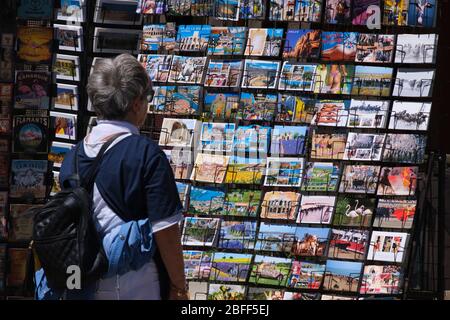 Donna che guarda le cartoline in mostra in un negozio di souvenir ad Arles, Francia, Europa Foto Stock