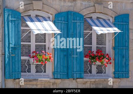 Due finestre chiuse con persiane blu e scatole di fiori ad Arles, Provenza, Francia meridionale, Europa Foto Stock