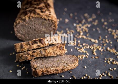 Pane di grano saraceno fatto in casa su sfondo scuro con grani. Pane fresco senza glutine, prodotti da forno tagliati a fette Foto Stock