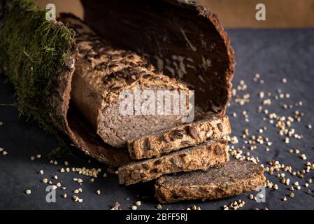 Pane di grano saraceno fatto in casa su sfondo scuro con grani. Pane fresco senza glutine, prodotti da forno tagliati a fette Foto Stock