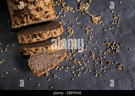 Pane di grano saraceno fatto in casa su sfondo scuro con grani. Pane fresco senza glutine, prodotti da forno tagliati a fette Foto Stock