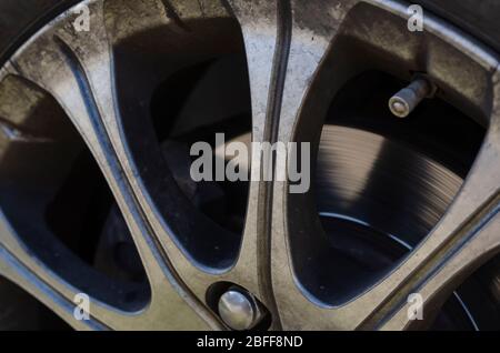 Primo piano vettura con cerchi in lega Fragment. Un'immagine dettagliata di un cerchio colato con tracce di sporco doron. Un colpo dopo il termine di una corsa di strada bandita. Selettivo Foto Stock
