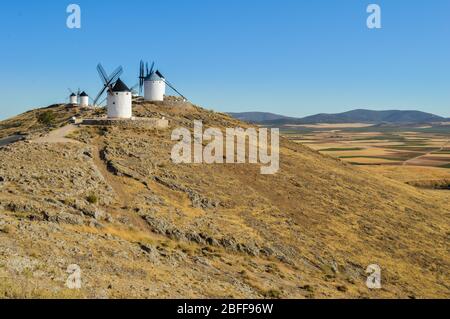 Tipici mulini a vento bianchi spagnoli (Molinos che appaiono a Don Quijote) circondati da un paesaggio secco a Consuegra, Toledo. Castilla la Mancha, Spagna. Foto Stock