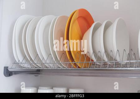 Rack di metallo per essiccazione piatti con grandi e bei utensili bianchi puliti. Cucina tradizionale a muro. Foto Stock