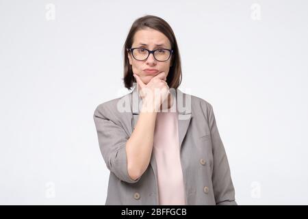 Donna abbastanza matura in occhiali guardando da parte con sguardo pensieroso che fa piano per il futuro. Generazione di idea per progetto di affari. Scatto studio Foto Stock