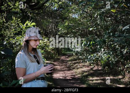 una bella donna modello bere yerba mate infusione mentre si cammina attraverso gli alberi Foto Stock